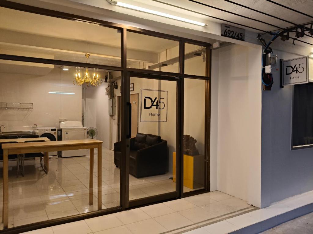 Glass station doors seen from inside, two adults and a child standing clear of the walkway beside a column, a folded stroller upright, and daylight catching dust on the automatic doors, 1600x1000